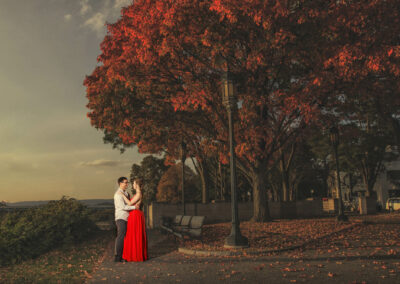 Engagement shoot in red dress in front of red tree on Front street